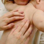 Close-up of a mother giving a gentle massage to her baby, showcasing tender care.